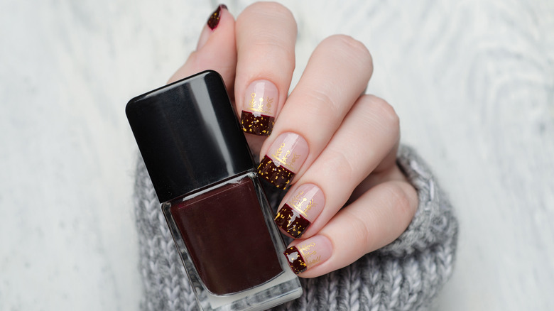 hand with brown french manicure gold flakes