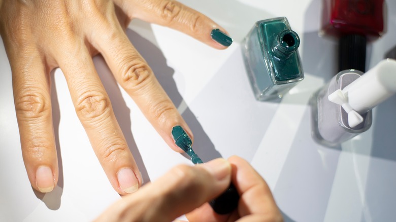 Woman paints her fingernails green