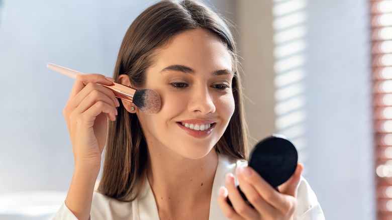 Woman putting on blush