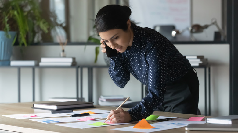 woman on phone call writing