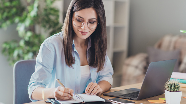 woman with glasses writing