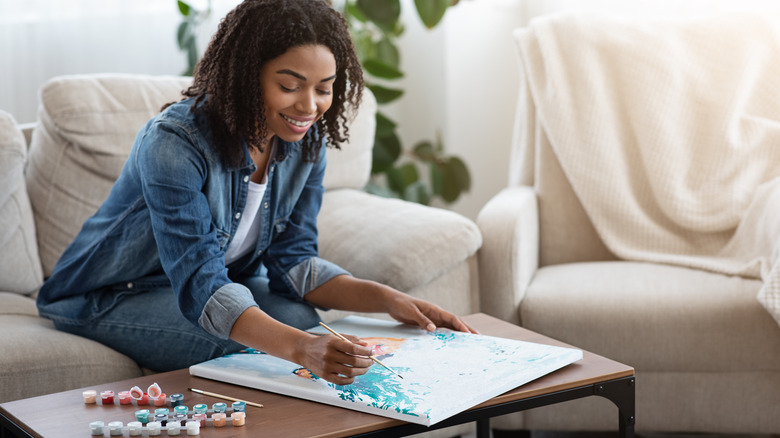 happy woman painting on couch