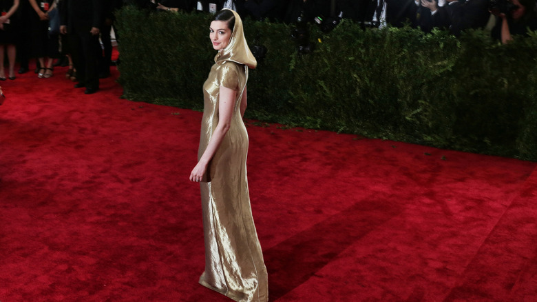 Anne Hathaway wearing gold on red carpet