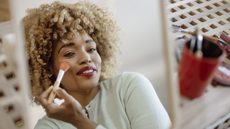 Woman with curly hair applying blush