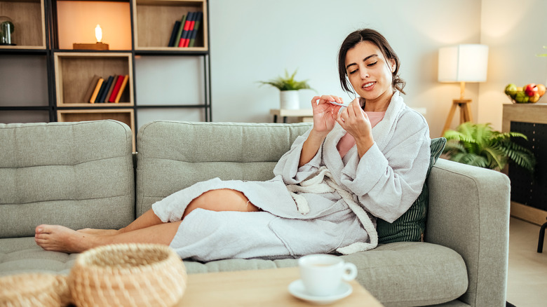 Woman in a bathrobe filing her nails