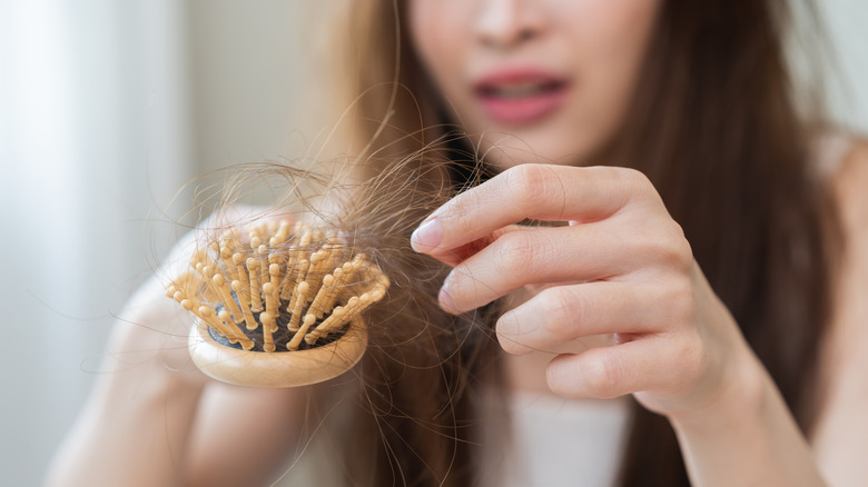 A person pulling built-up clogged hair out of a hair brush