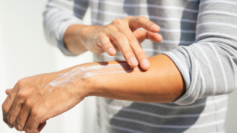 man applying sunscreen on forearm 