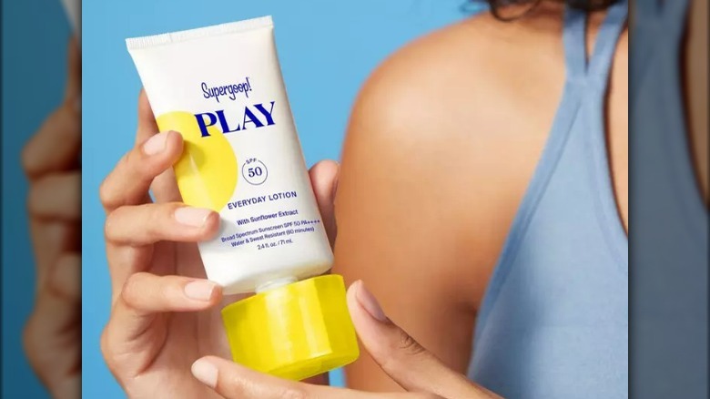 Person holding a sunscreen tube