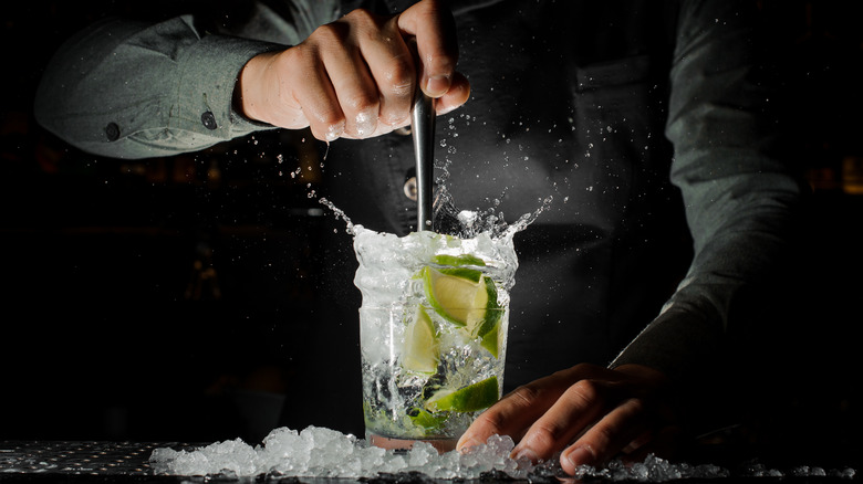 Bartender muddles a Caipirinha cocktail