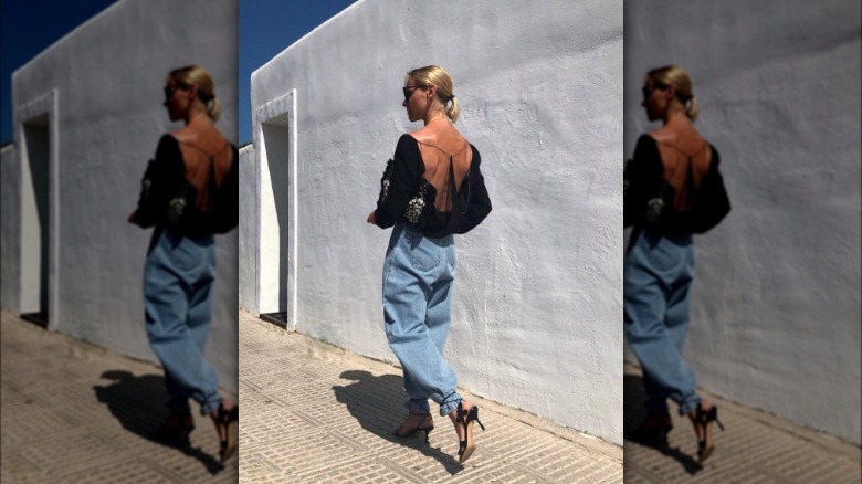 A woman wearing baggy jeans with a backless top