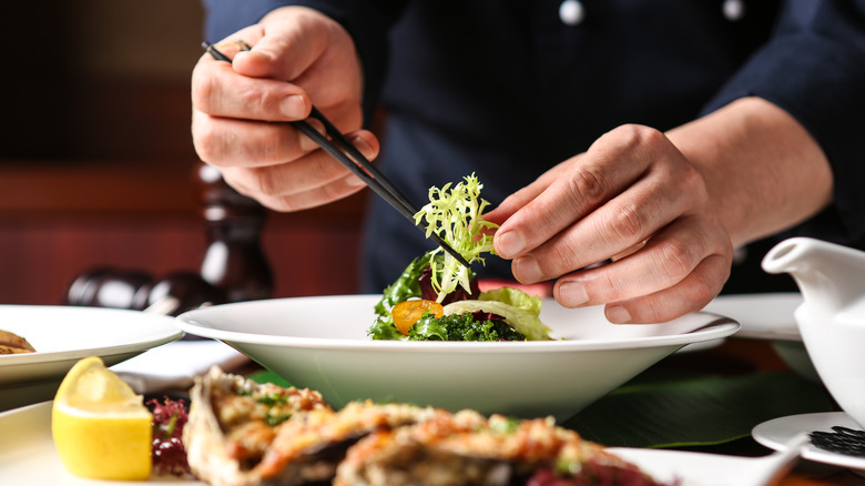 hands plating food at restaurant