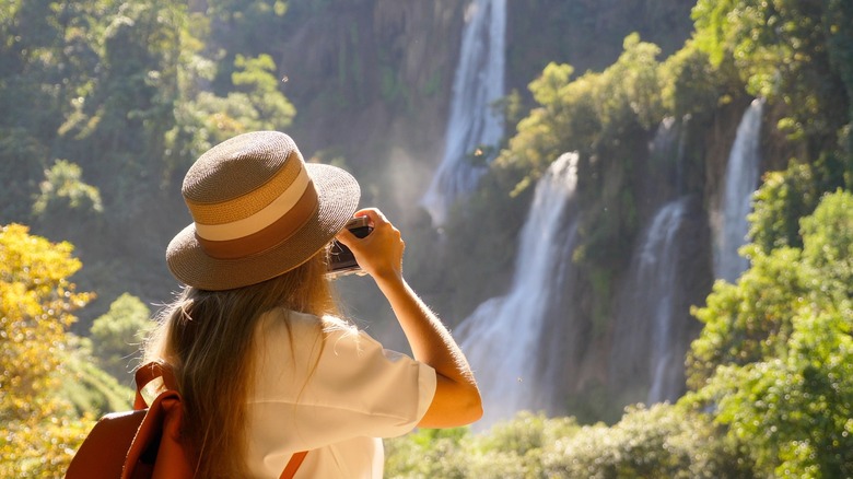 woman taking picture of waterfalls