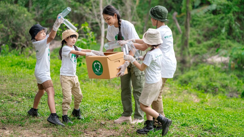 woman and kids recycling plastic bottles in park