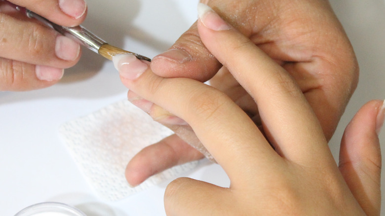 applying acrylic on woman's nails