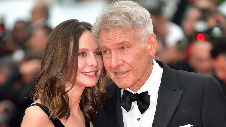 Harrison Ford and Calista Flockhart leaning close together on the red carpet.