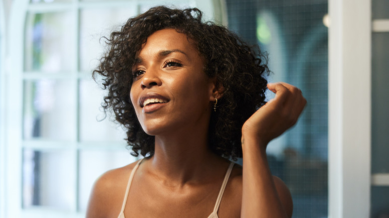 Smiling woman styling curly hair