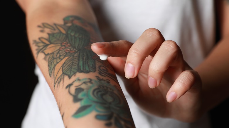 woman applying cream to tattoo