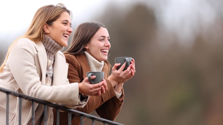 Two women standing outside holding mugs