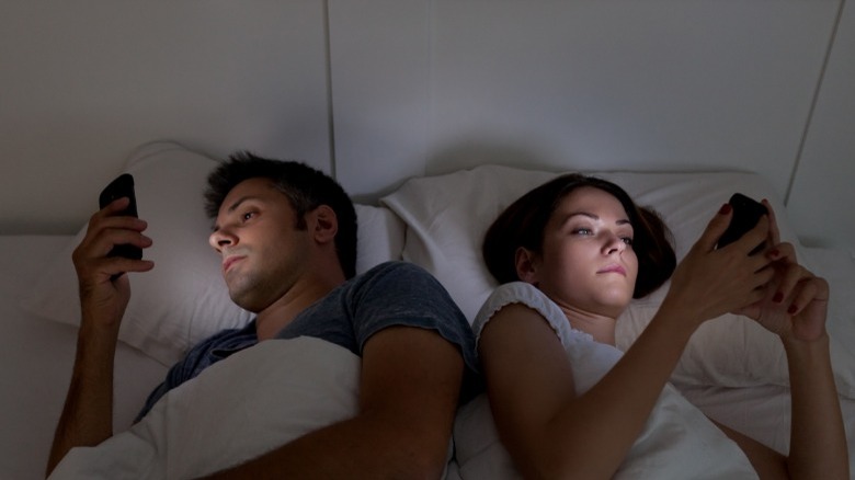 Couple in bed on phones