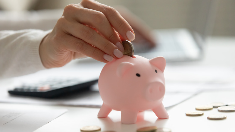 Woman saves coins in piggy bank