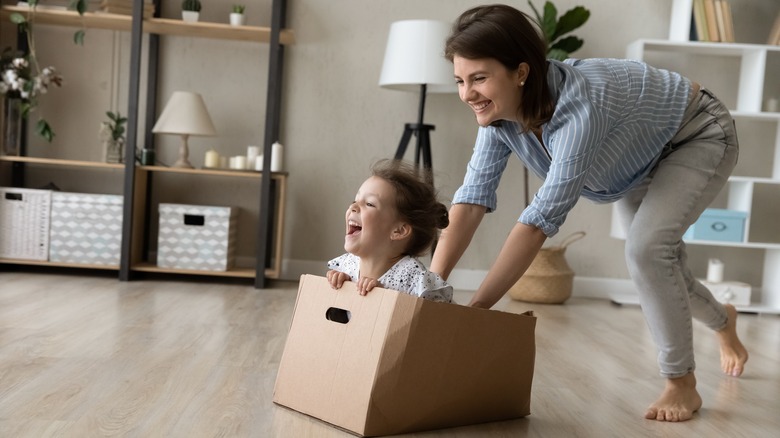 Woman pushing a small child sitting in a box