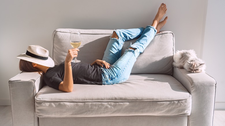 Woman lying on her couch with a glass of wine