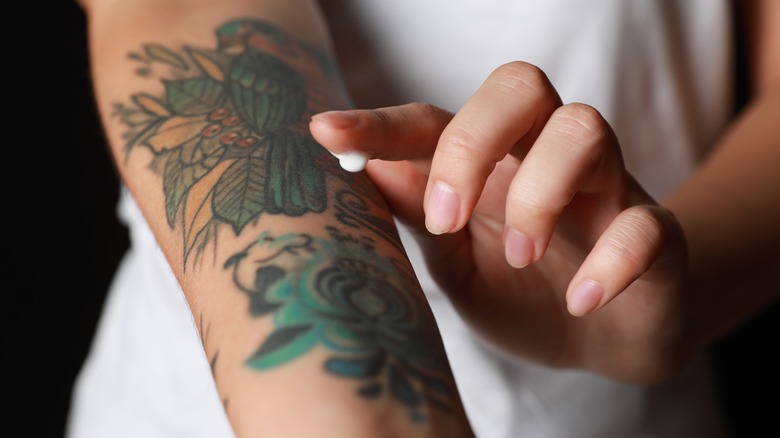 Woman applying cream to tattoo