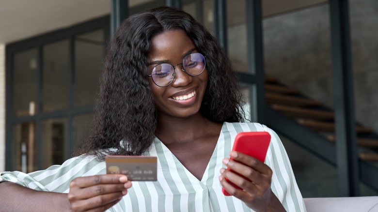 Woman holding credit card and phone while smiling