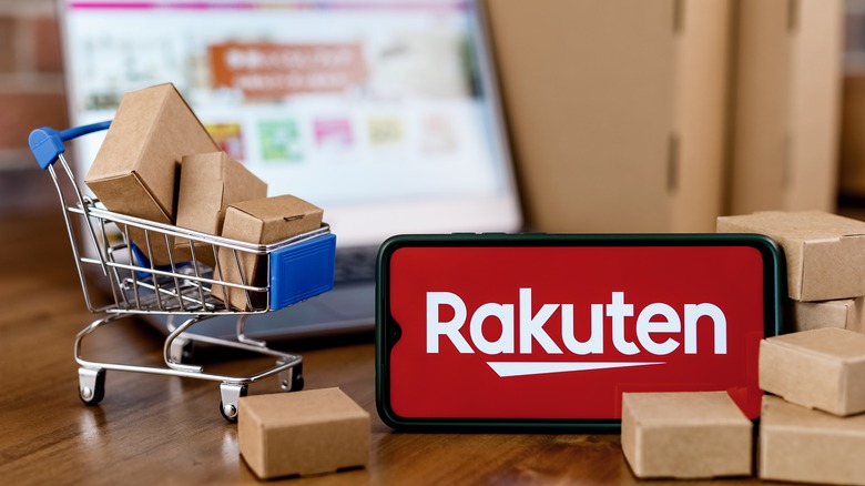 Phone displaying Rakuten logo in front of laptop