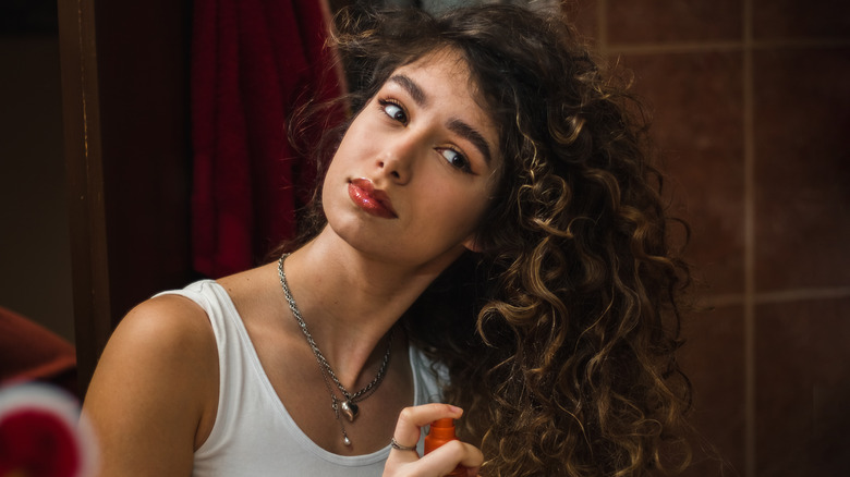 woman adding oil to curly hair 