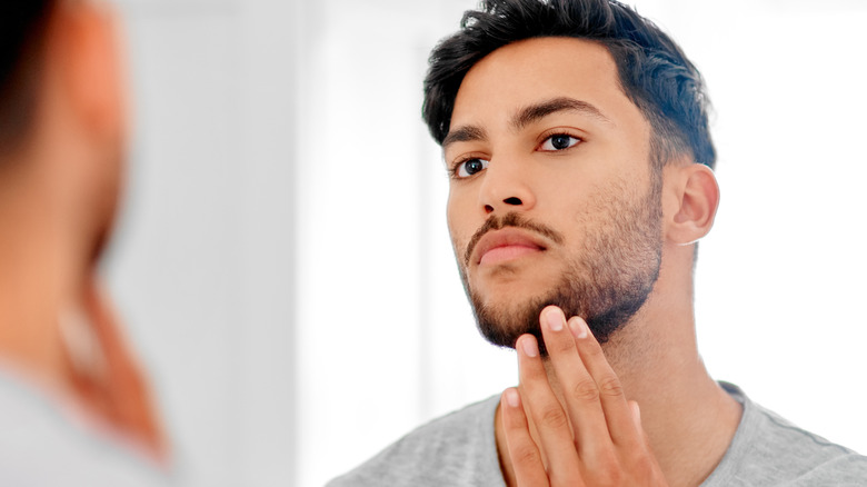 Man examining beard in mirror