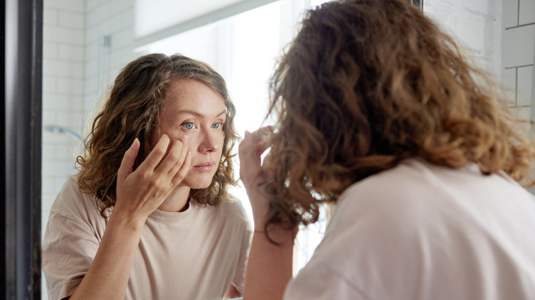 Woman with curly hair applying eye cream