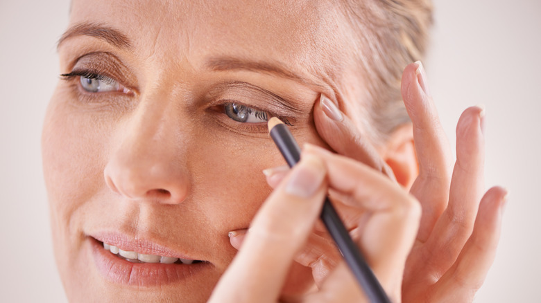 Mature woman applying eyeliner