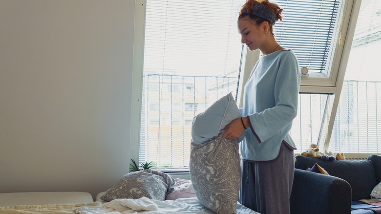 Young woman changing pillowcase