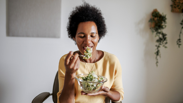 An older woman with natural hair eating a salad.