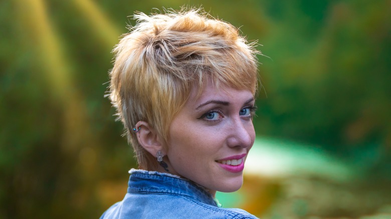 A woman with a textured blond pixie wearing a denim jacket