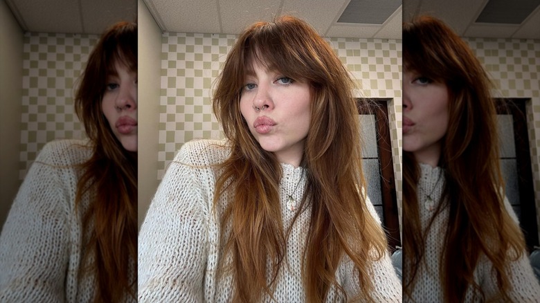 A woman with a brown shag haircut pouting at the camera