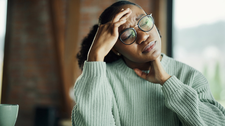 A woman feeling stressed and rubbing her head.