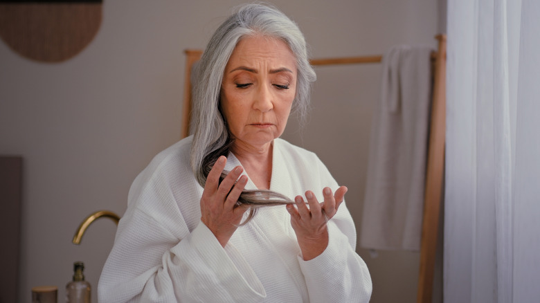 An older woman with gray hair admires her ends.