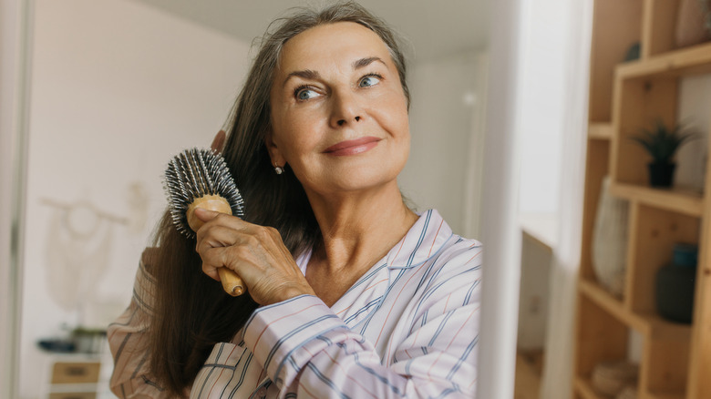 Older woman brushing her long gray hair