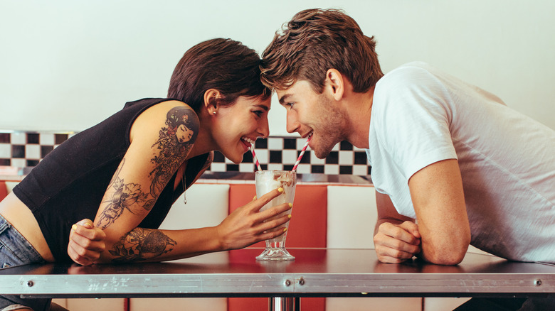 Happy couple sharing milkshake