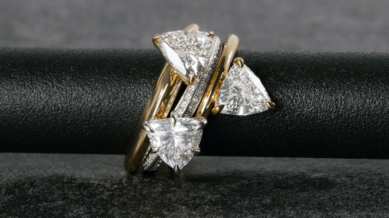 three triangular shaped diamond engagement rings on a metal pole