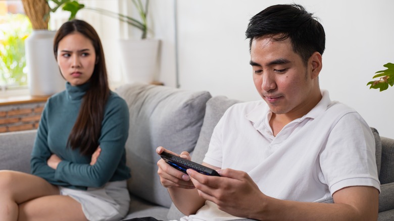 Woman angrily looking at man texting