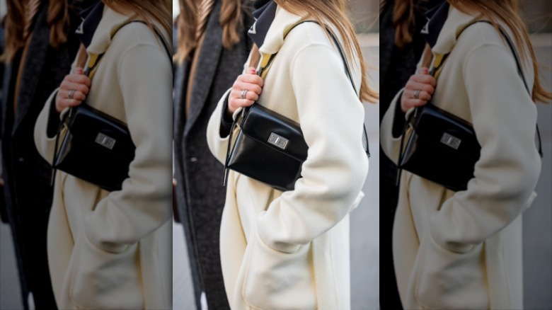 woman holding black glossy shoulder bag