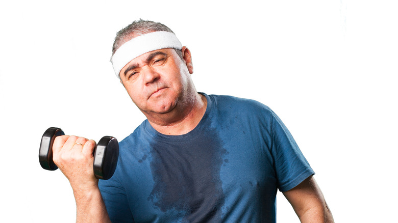 Sweaty man lifting free weights