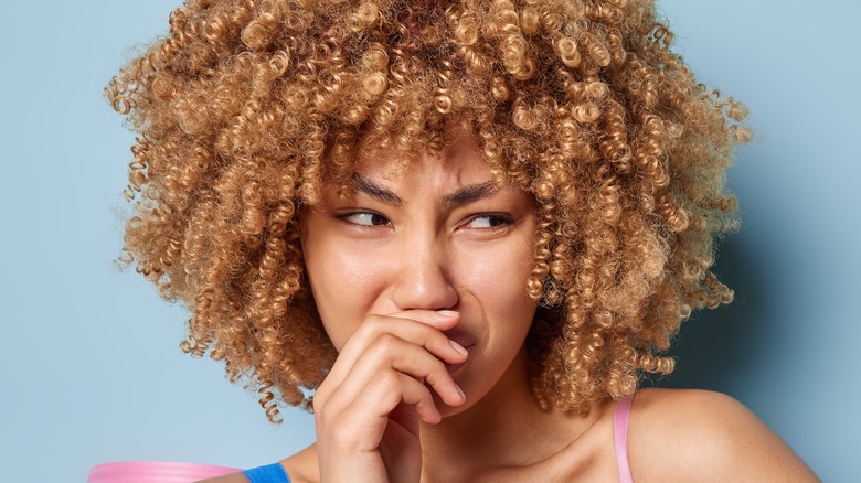 Curly-haired woman frowning at bad smell