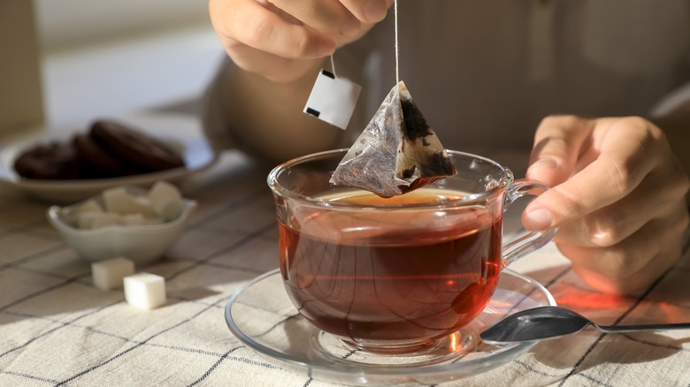 person steeping tea in mug