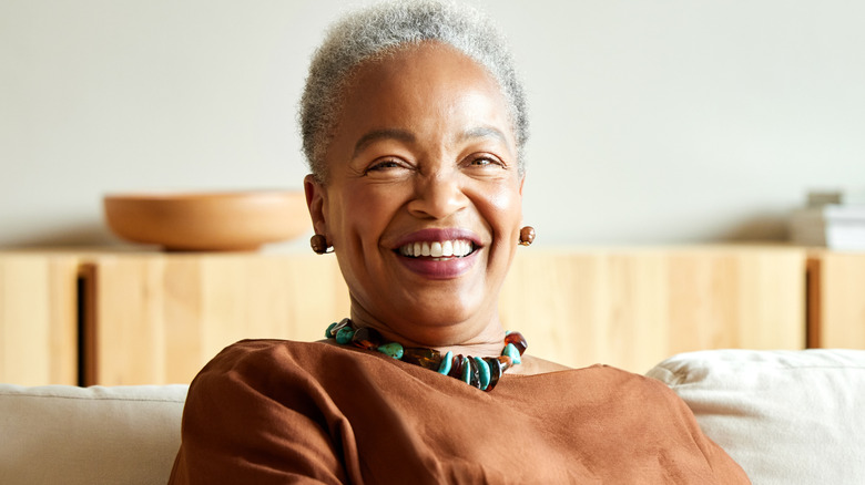 A smiling older woman wearing a large turquoise beaded necklace and matching earrings.