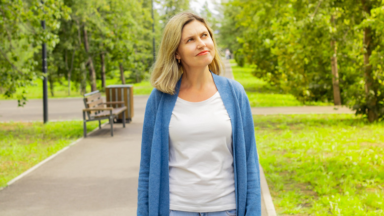 A middle-aged woman wearing a T-shirt and cardigan outside.