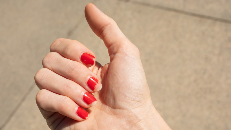 Person with chipped red nail polish